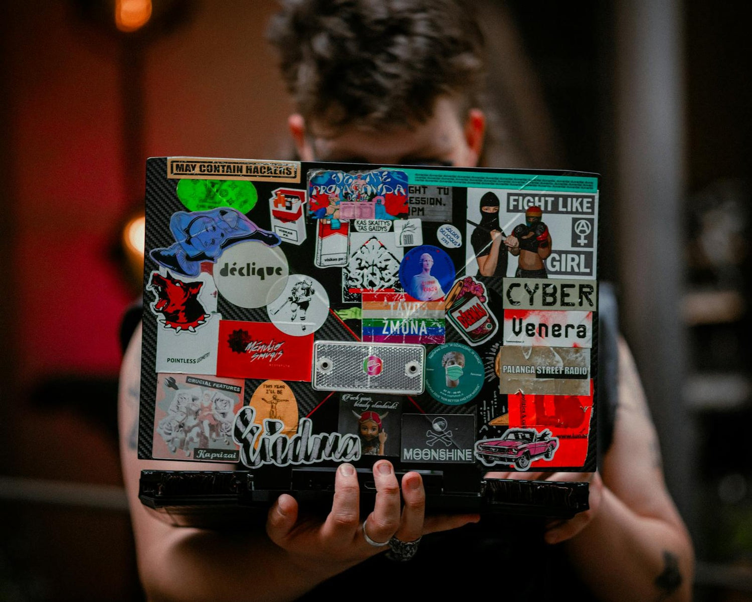 A person holds a laptop with vibrant stickers, showcasing creativity and personal expression.