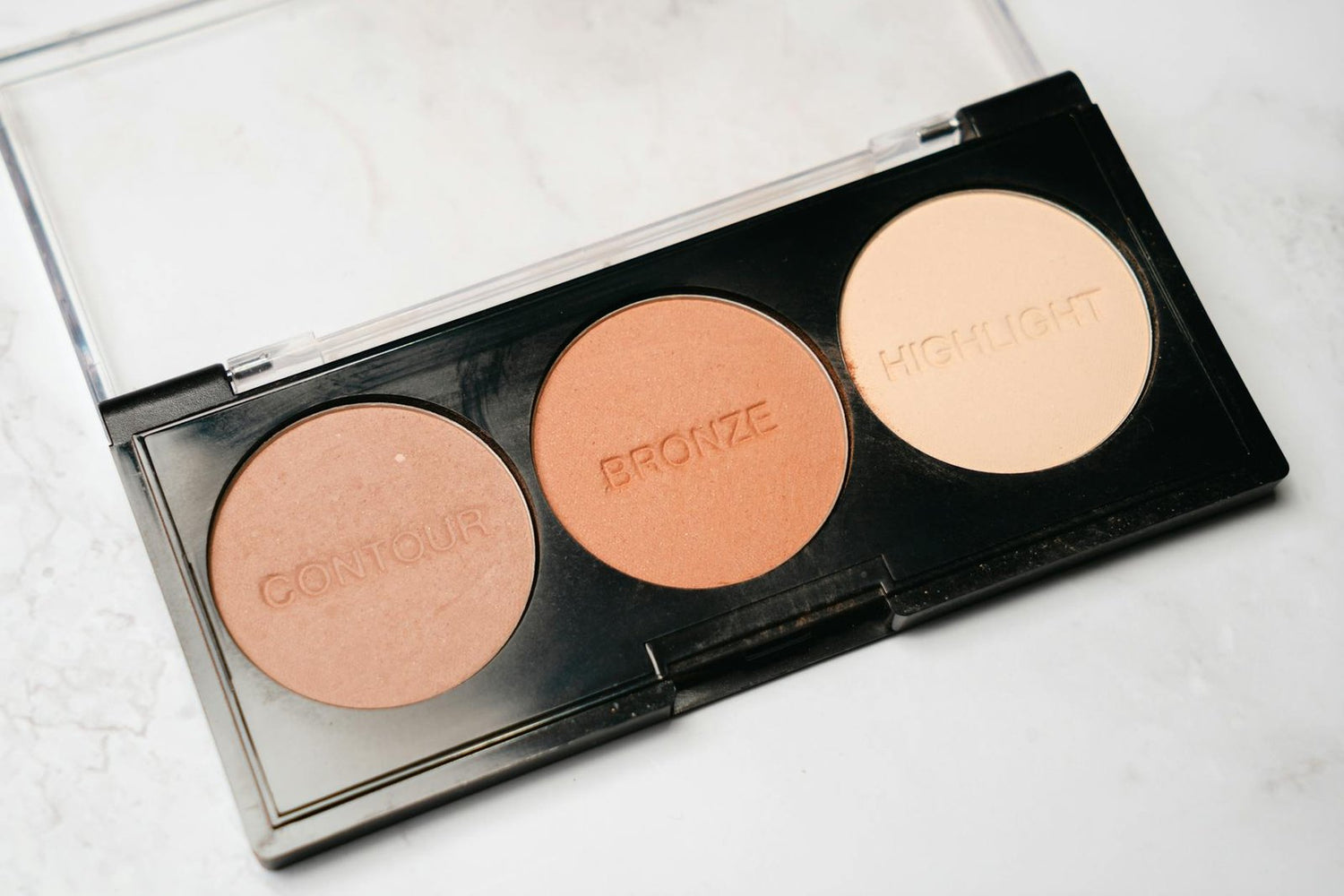 Close-up of a makeup palette featuring contour, bronze, and highlight powders.