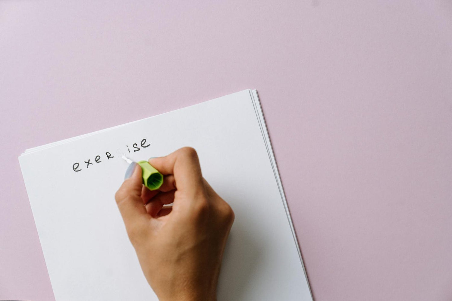 A hand using correction fluid to fix a spelling error on paper.